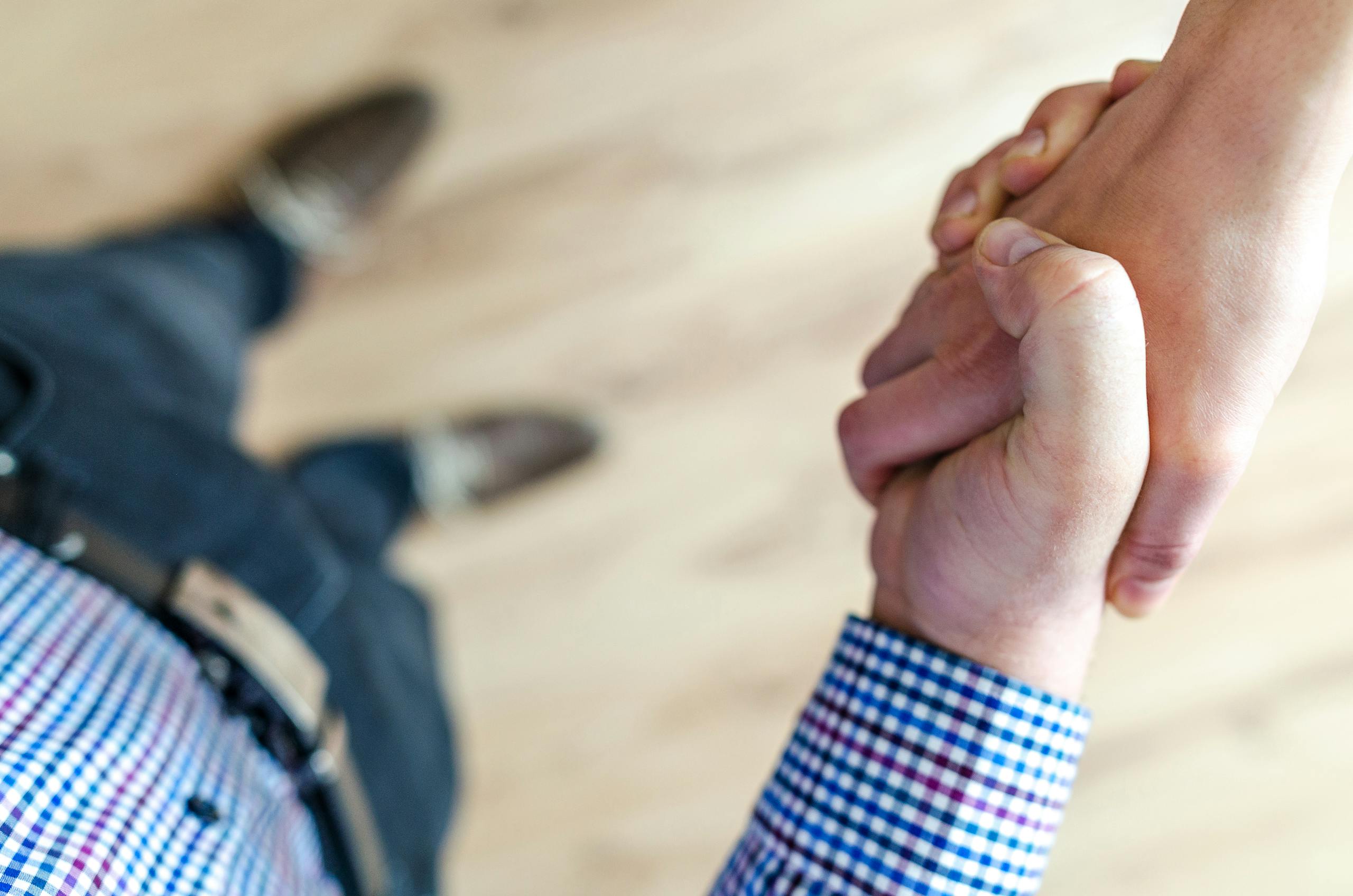 A hand signs a formal contract with a pen on a wooden desk.